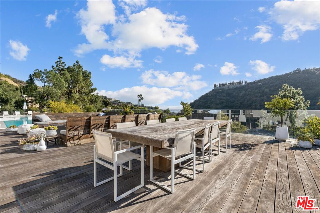1650 Clear View Drive Beverly Hills, CA 90210 - Photo 23 of 31 a view of a patio with table and chairs with wooden floor and fence