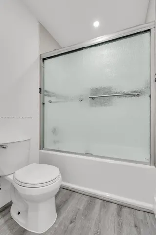 a view of an empty room with wooden floor and window