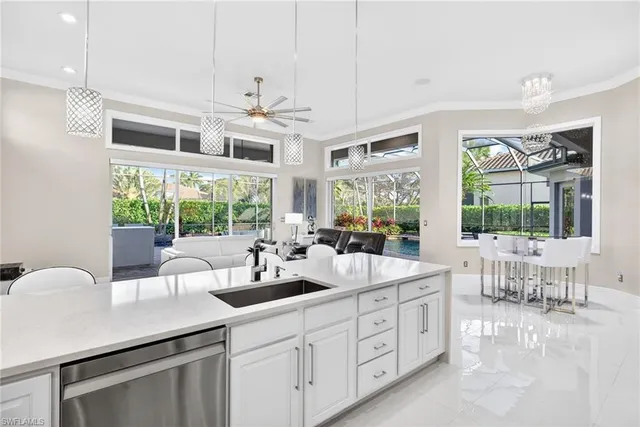 a large kitchen with kitchen island a large window cabinets a sink and stainless steel appliances