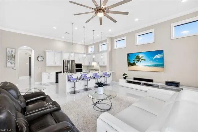 a living room with furniture and a flat screen tv with kitchen view