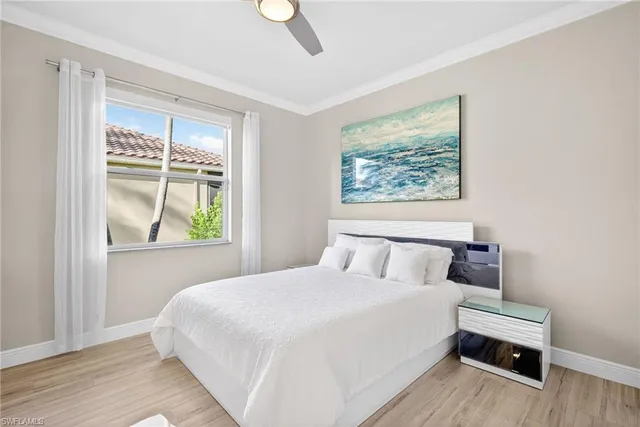 a bedroom with a bed a window and potted plant on the dresser