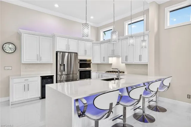 a kitchen with stainless steel appliances a refrigerator a stove a sink dishwasher a dining table and chairs with wooden floor