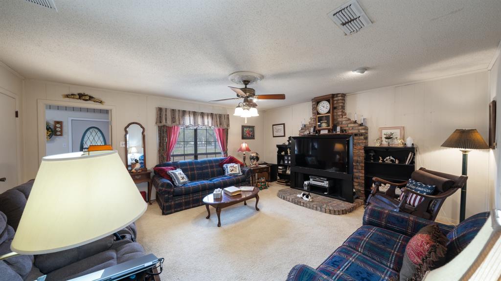460 VZ County Road Canton, TX 75103 - Photo 10 of 24 Living area with carpet flooring, a textured ceiling, ceiling fan, and ornamental molding, the wood burning stove is behind the Big Screen