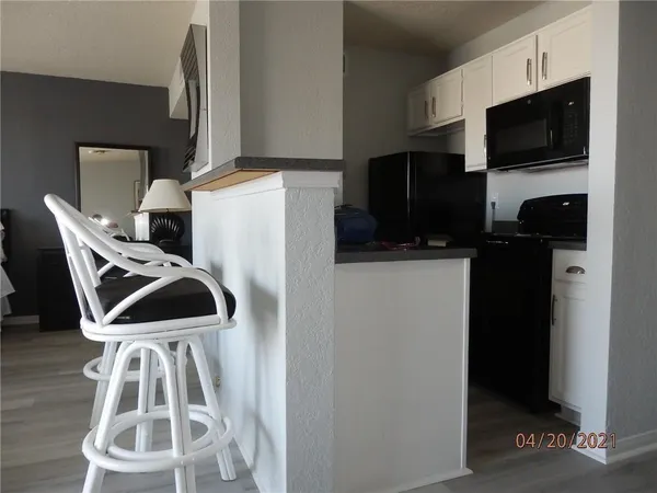 a view of a kitchen with fridge and wooden floor