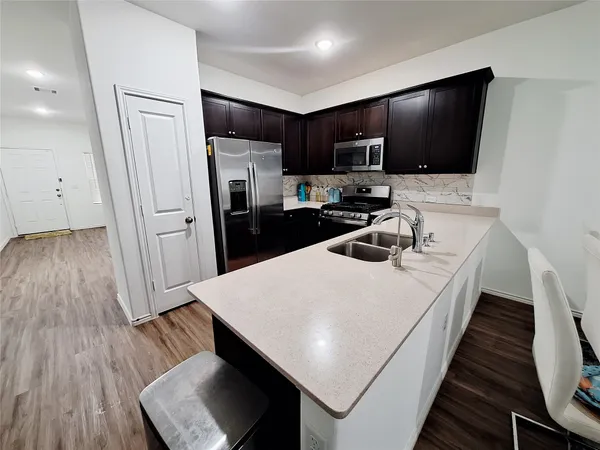 a kitchen with sink a refrigerator and microwave