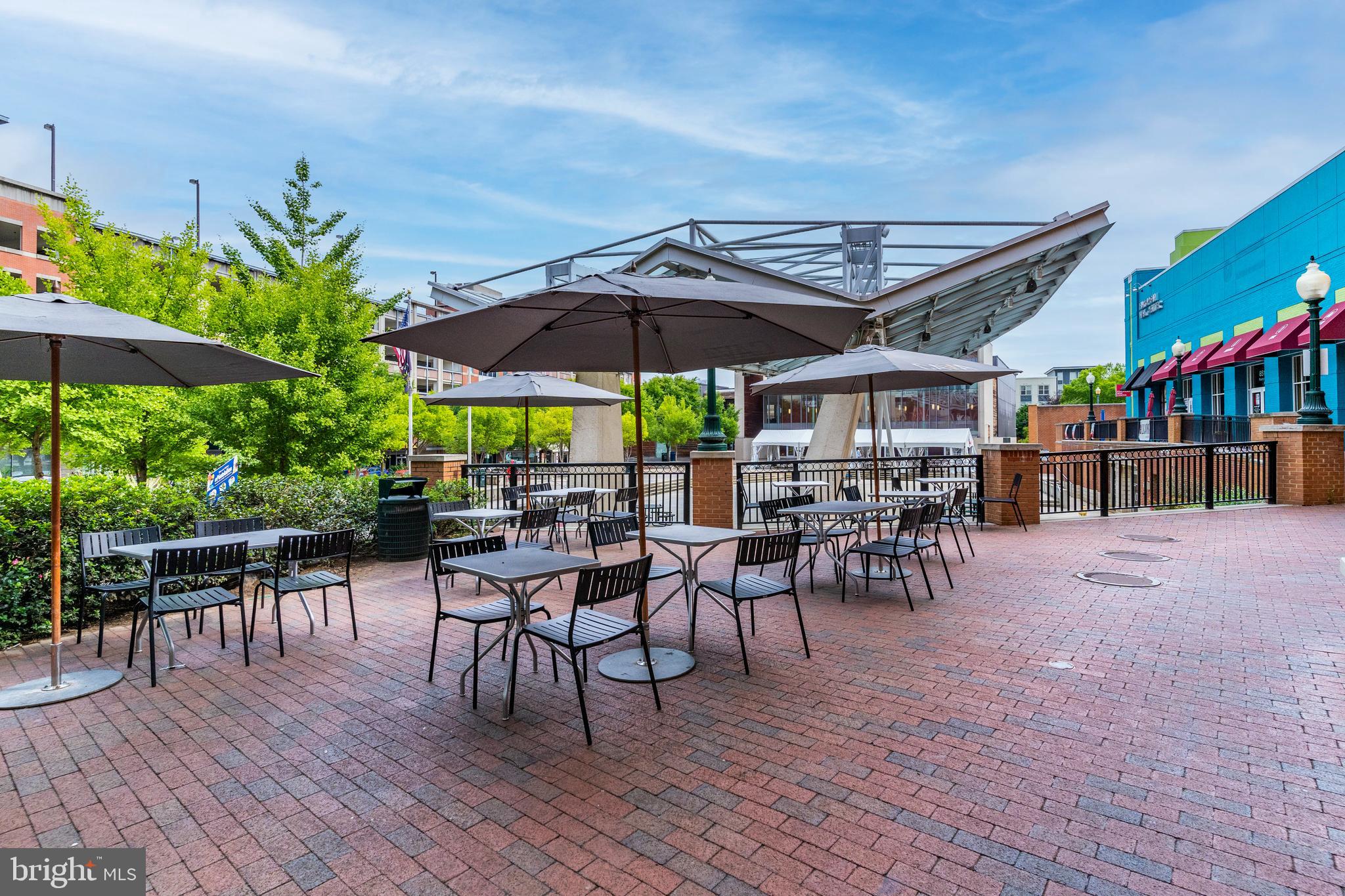 1320 Fenwick Lane, Unit 304 Silver Spring, MD 20910 - Photo 17 of 64 a view of a roof deck with table and chairs under an umbrella with wooden floor