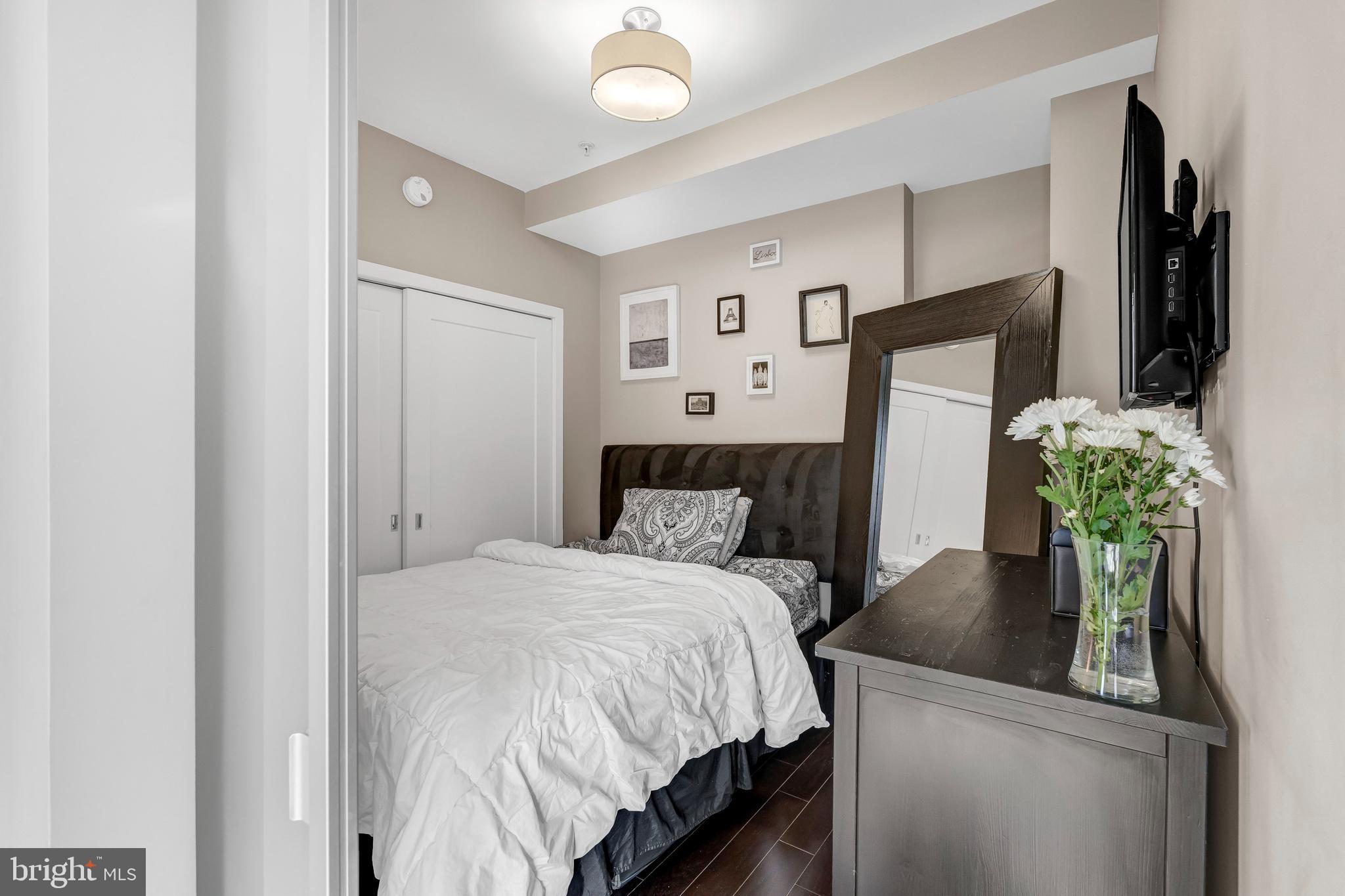1320 Fenwick Lane, Unit 304 Silver Spring, MD 20910 - Photo 23 of 64 a bedroom with a bed potted plant on the counter and a mirror