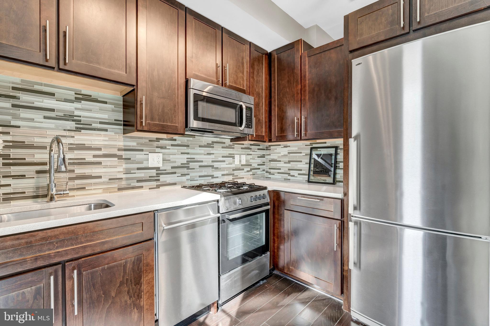 1320 Fenwick Lane, Unit 304 Silver Spring, MD 20910 - Photo 43 of 64 a kitchen with stainless steel appliances and wooden cabinets