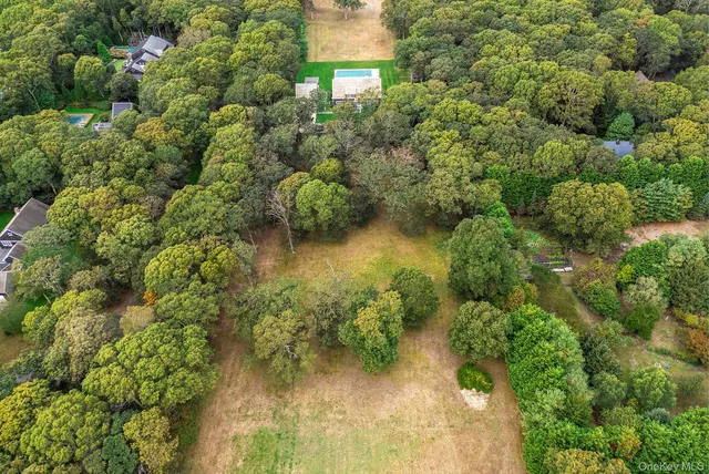 an aerial view of residential house with outdoor space and trees all around