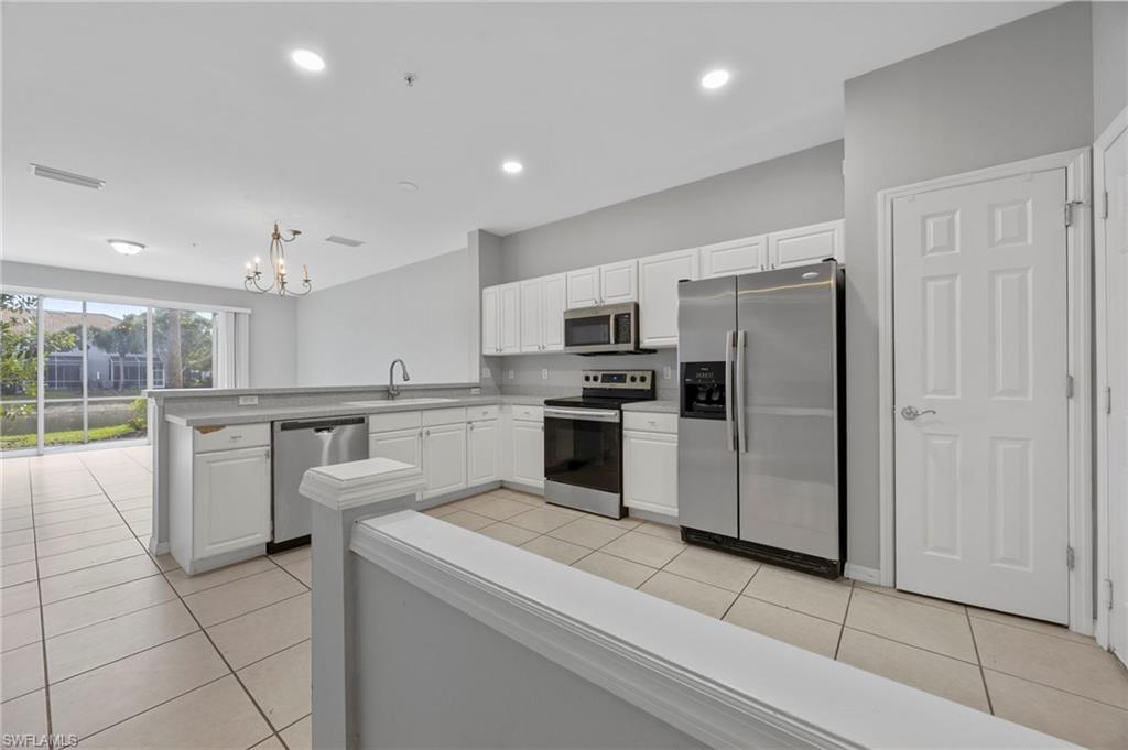 15930 Marcello Circle, Unit 242 Naples, FL 34110 - Photo 4 of 32 a kitchen with white cabinets and stainless steel appliances
