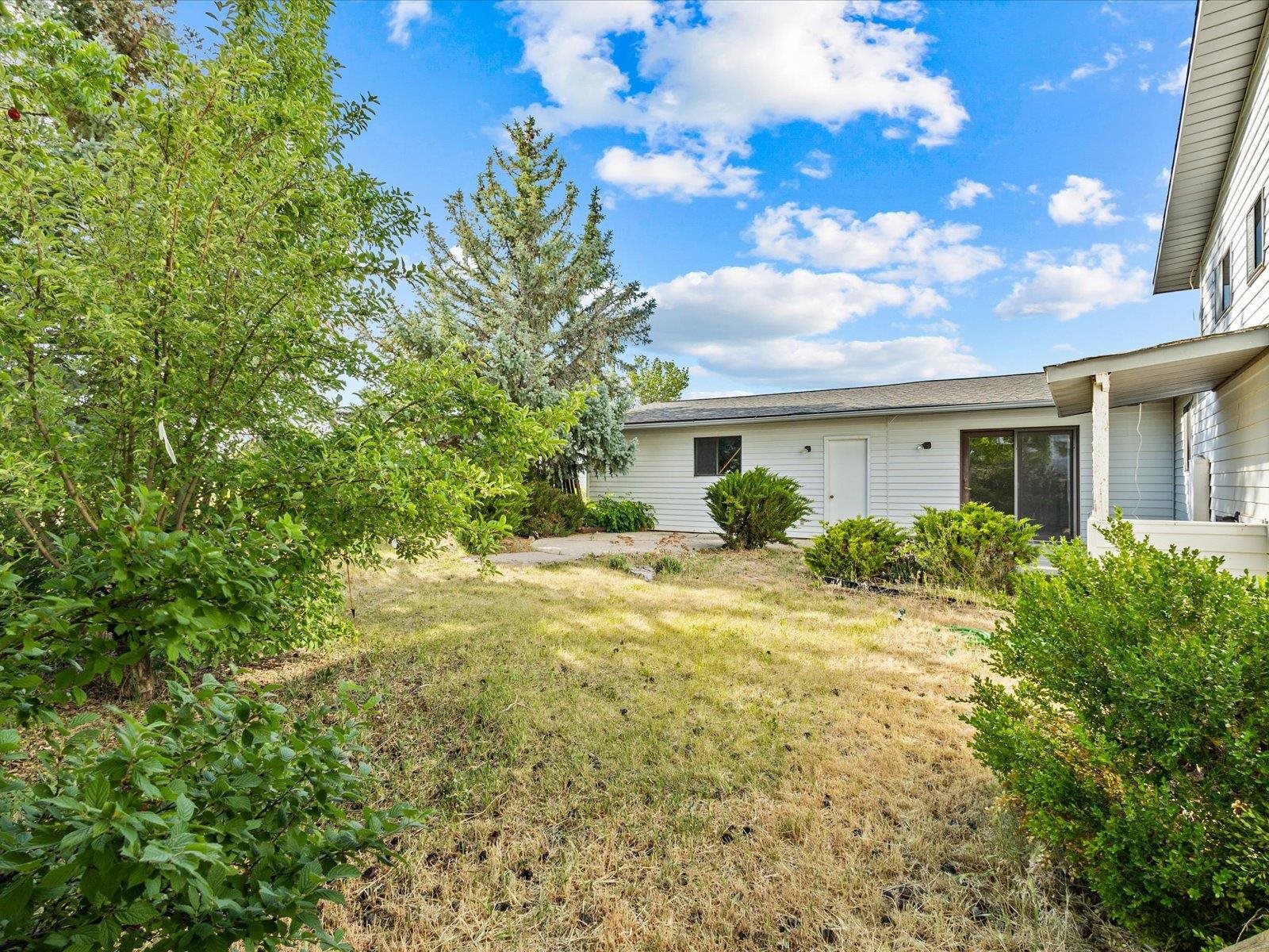 1425 19 Road Fruita, CO 81521 - Photo 38 of 42 a view of a white house next to a yard with plants and trees