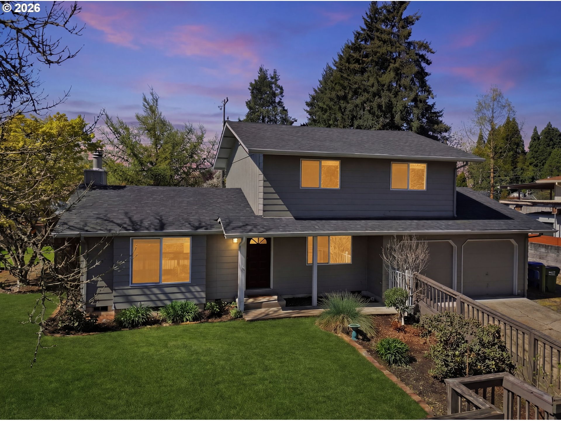 a front view of a house with a garden and tree