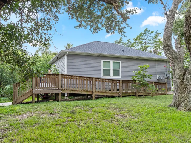 a view of a house with a backyard and a wooden deck