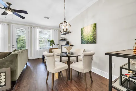 a dining room with wooden floor a chandelier a glass table and chairs