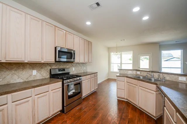 a kitchen with stainless steel appliances granite countertop white cabinets granite counter tops and a hard wood floors