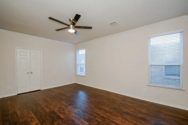 a view of a room with wooden floor a ceiling fan and windows