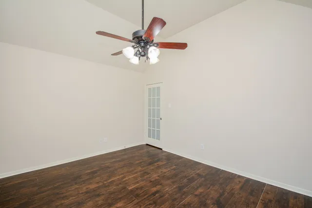 an empty room with wooden floor fan and window