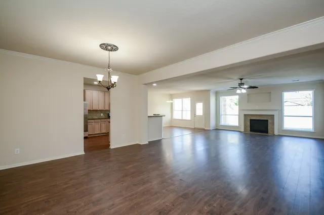 an empty room with wooden floor fireplace and windows