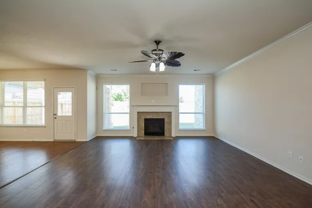 an empty room with wooden floor fireplace chandelier and windows