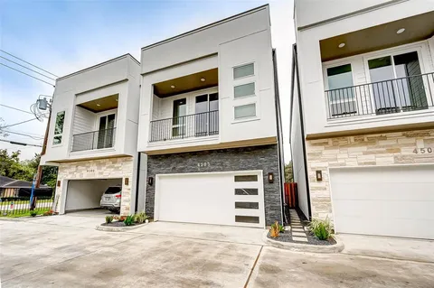 a large kitchen with stainless steel appliances granite countertop a stove a sink dishwasher a refrigerator white cabinets wooden floor and a large window