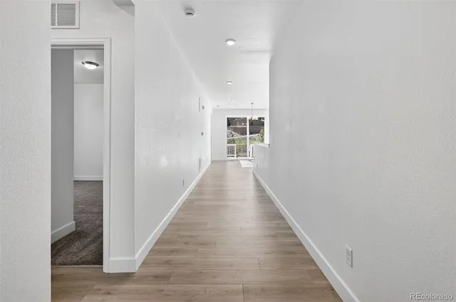 a view of a hallway with wooden floor and staircase