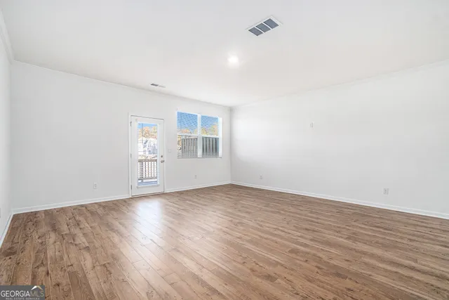 an empty room with wooden floor and windows