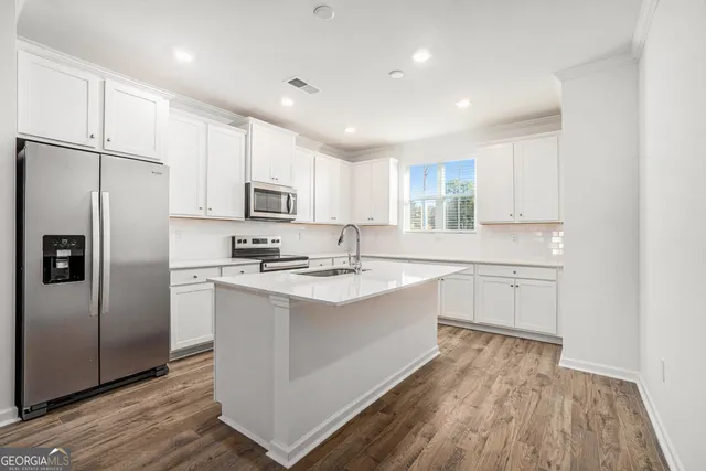 a kitchen with stainless steel appliances granite countertop a refrigerator a sink dishwasher a stove with wooden floors and cabinets