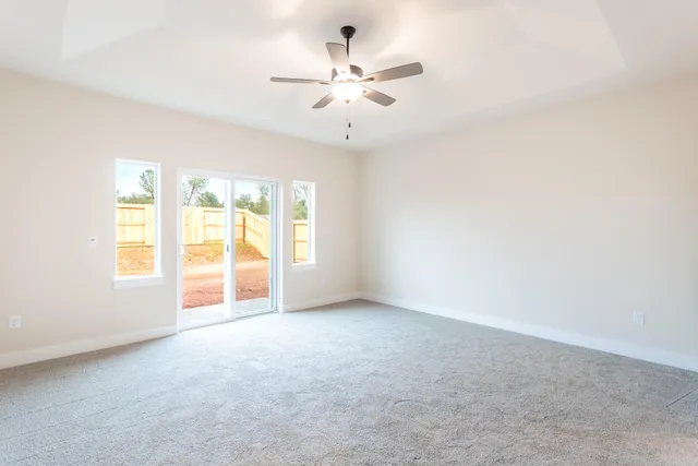 an empty room with windows and ceiling fan