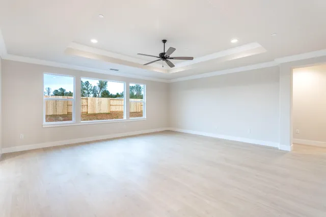 an empty room with windows and chandelier fan