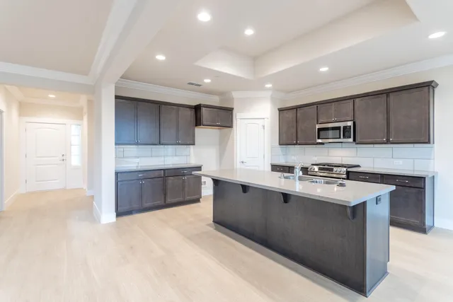 a large kitchen with stainless steel appliances granite countertop a stove refrigerator sink and cabinets