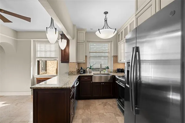 a kitchen with granite countertop a refrigerator a sink a stove and furniture