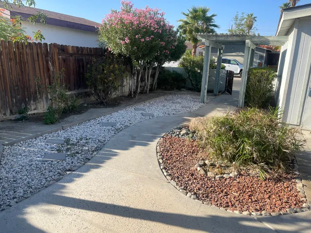 a view of a house with a small yard and large tree