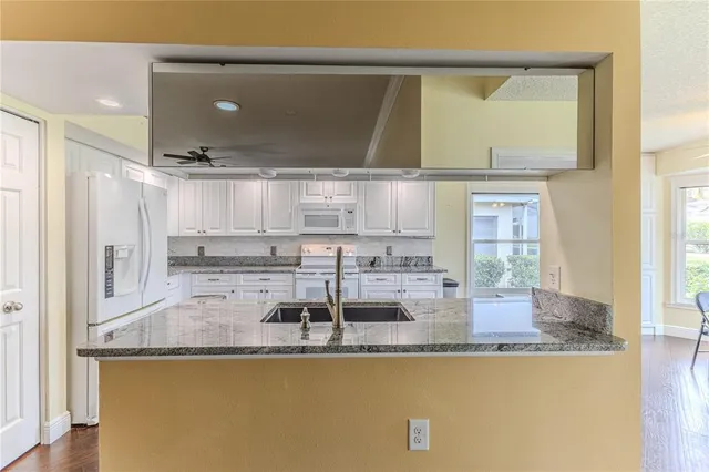 a kitchen with granite countertop white cabinets and white appliances