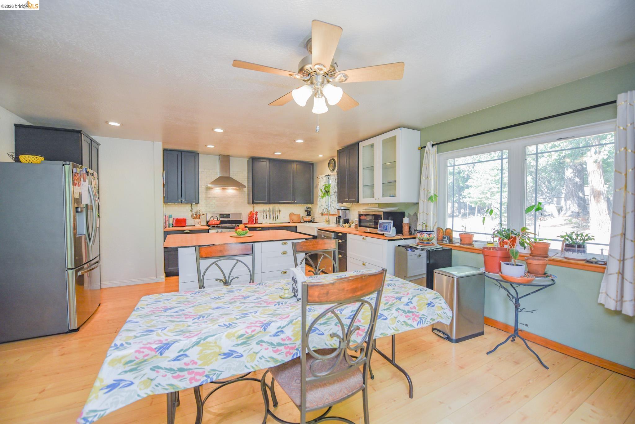 23615 Elizabeth Peak Road Twain Harte, CA 95383 - Photo 11 of 38 Kitchen featuring stainless steel appliances, glass insert cabinets, a kitchen island, wall chimney exhaust hood, and light wood finished floors