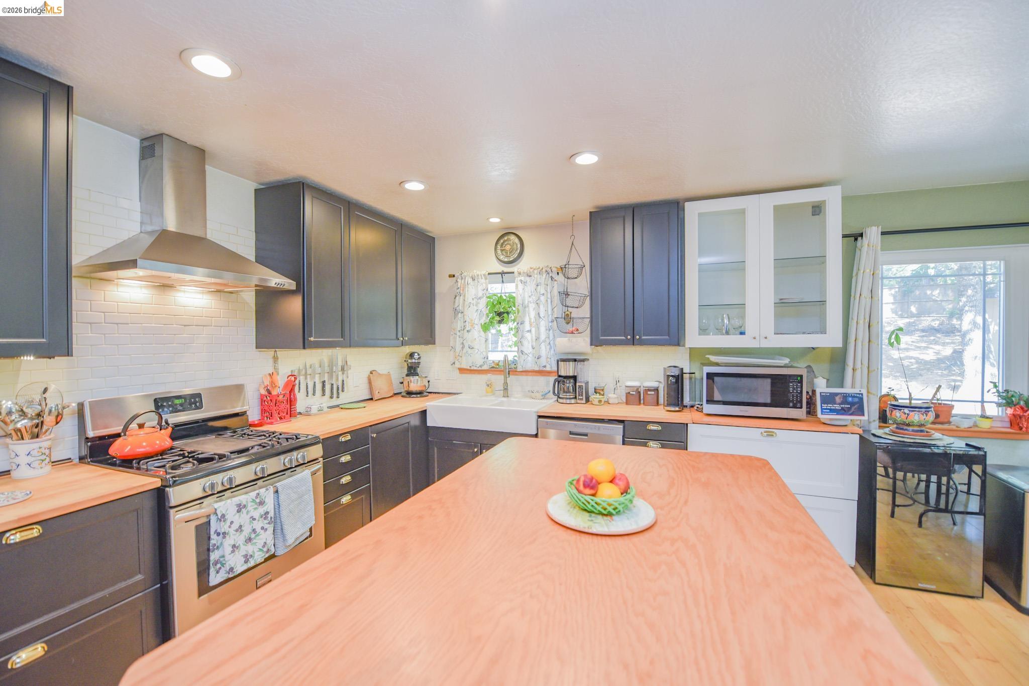 23615 Elizabeth Peak Road Twain Harte, CA 95383 - Photo 10 of 38 Kitchen featuring stainless steel appliances, wall chimney range hood, butcher block counters, recessed lighting, and wood finished floors