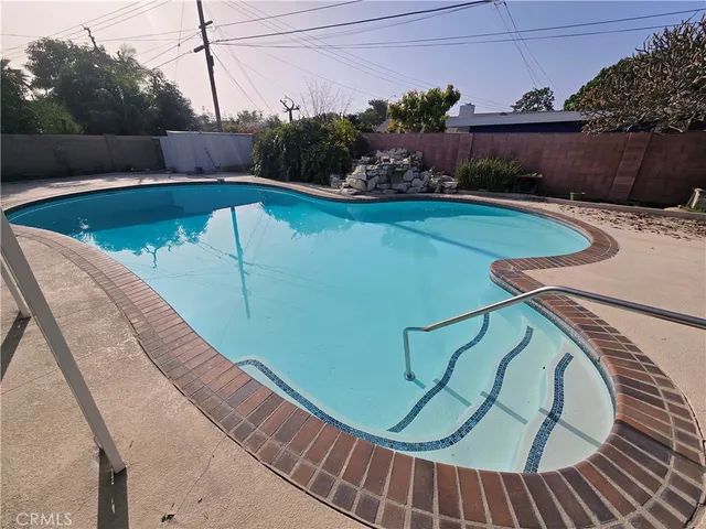 a view of swimming pool with seating area and trees in the background