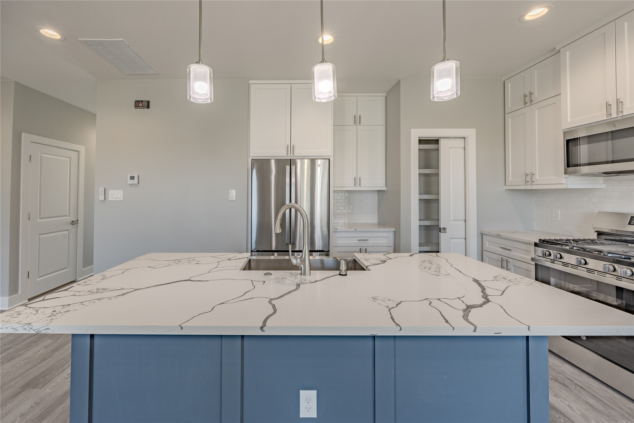 737 Ebenezer Lane Brenham, TX 77833 - Photo 3 of 25 a kitchen with a sink a stove a refrigerator and white cabinets with wooden floor