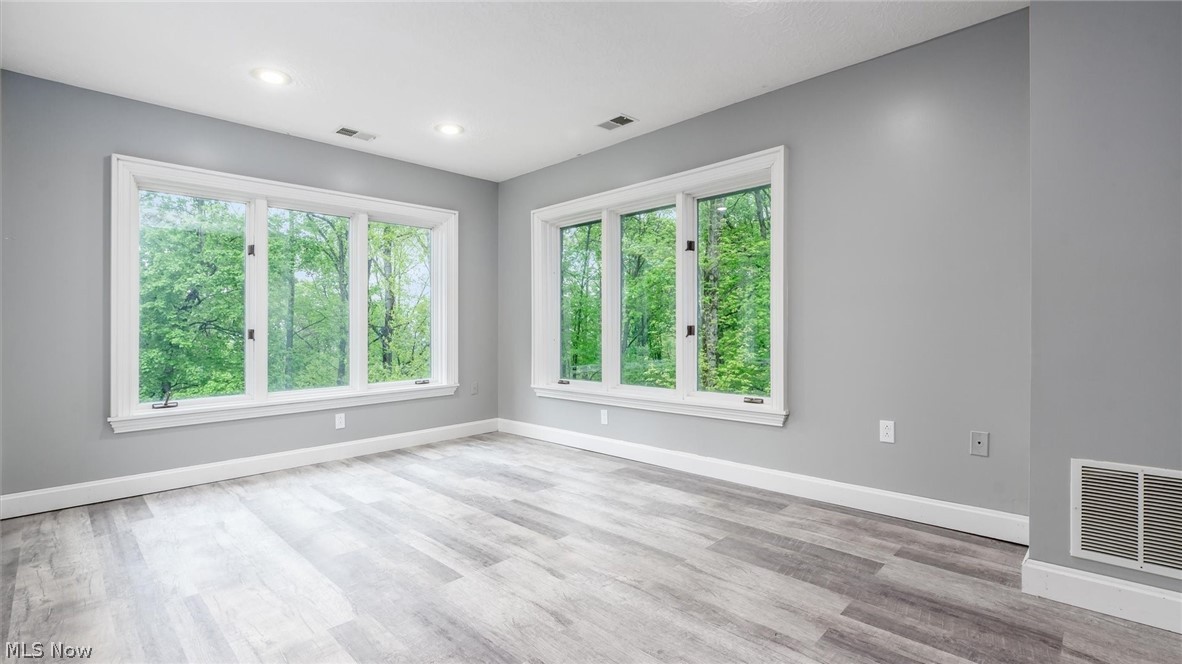 2531 Nicholas Lane Dresden, OH 43821 - Photo 21 of 40 Bright interior space with multiple large windows, wood-finish flooring, recessed ceiling lighting, and light gray wall finishes