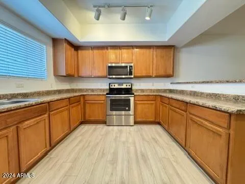 a kitchen with granite countertop a sink cabinets stainless steel appliances and a window