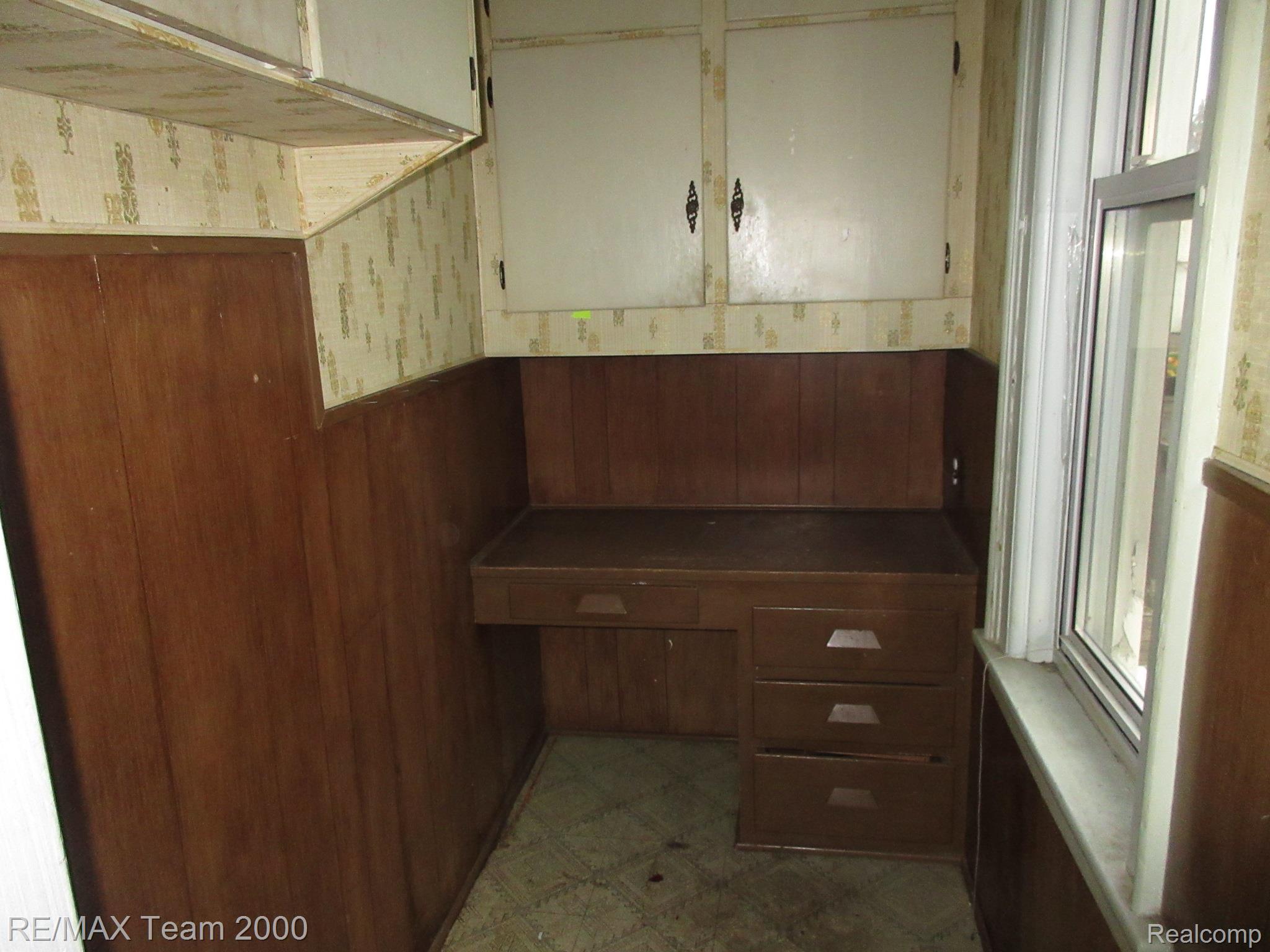 604 Smith Street Monroe, MI 48161 - Photo 15 of 24 Compact room featuring a built-in wood-finish desk with drawers, overhead white cabinetry with dark hardware, and a single window