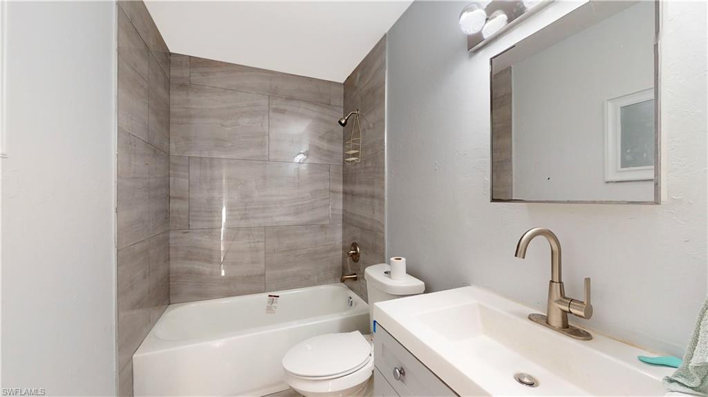 3903 35th Street Southwest Lehigh Acres, FL 33976 - Photo 14 of 16 a bathroom with a toilet a sink and a bathtub