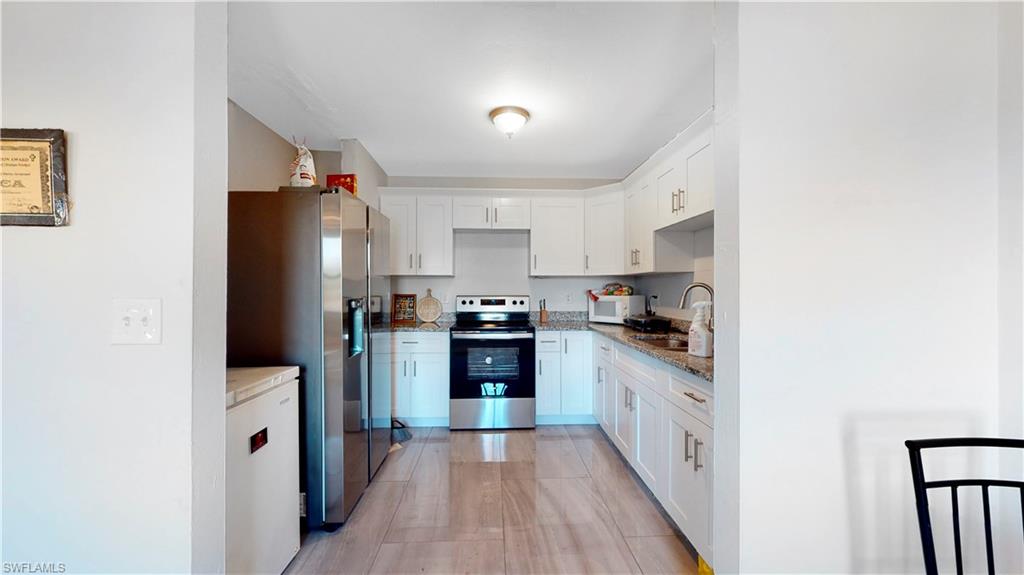 3903 35th Street Southwest Lehigh Acres, FL 33976 - Photo 7 of 16 a kitchen with stainless steel appliances a refrigerator sink and cabinets