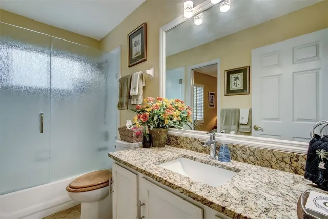 a bathroom with a granite countertop sink a toilet and a mirror