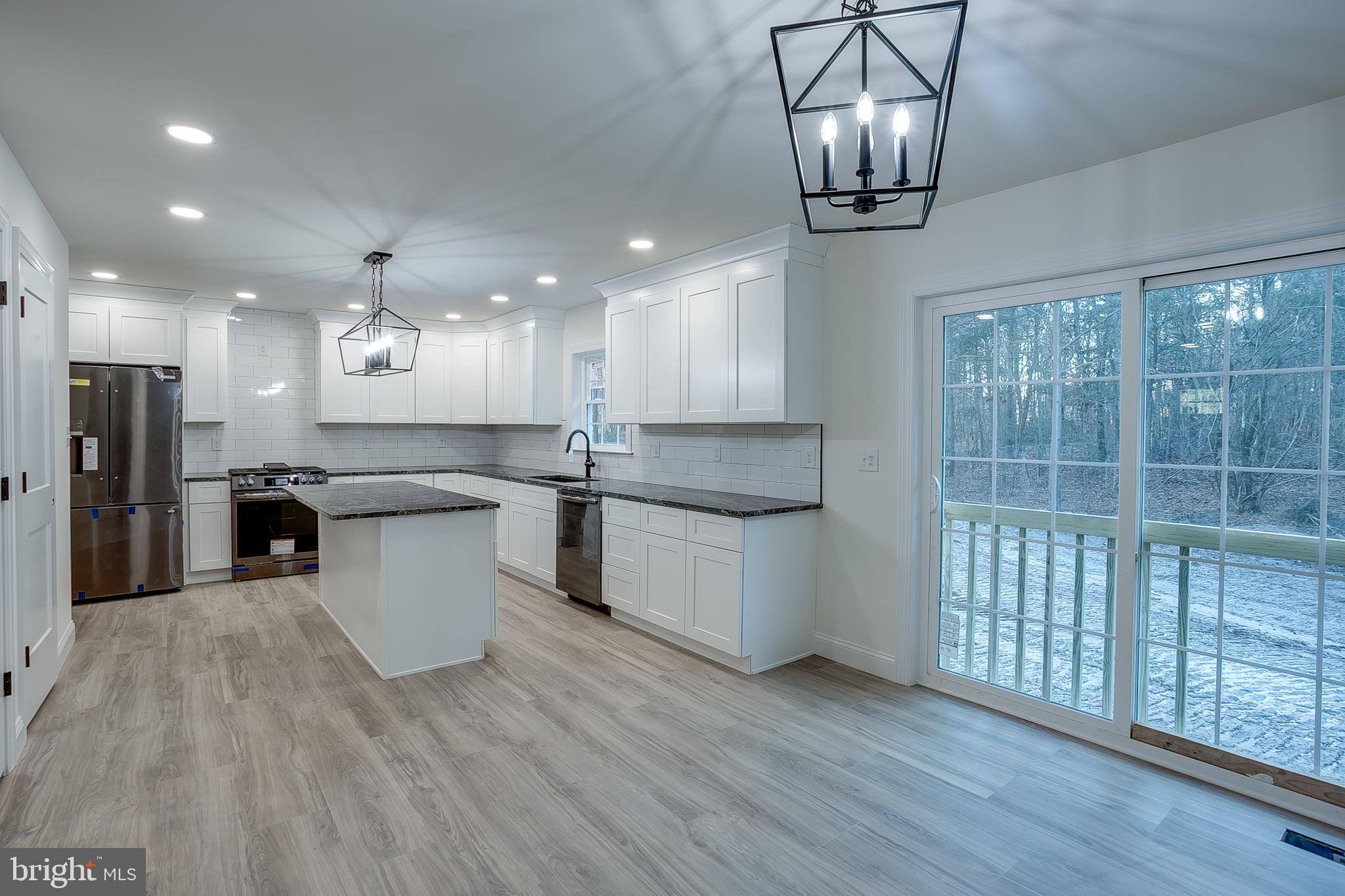 1427 Williamstown Erial Road Sicklerville, NJ 08081 - Photo 9 of 27 a kitchen with stainless steel appliances kitchen island granite countertop a stove a sink a refrigerator and white cabinets with wooden floor