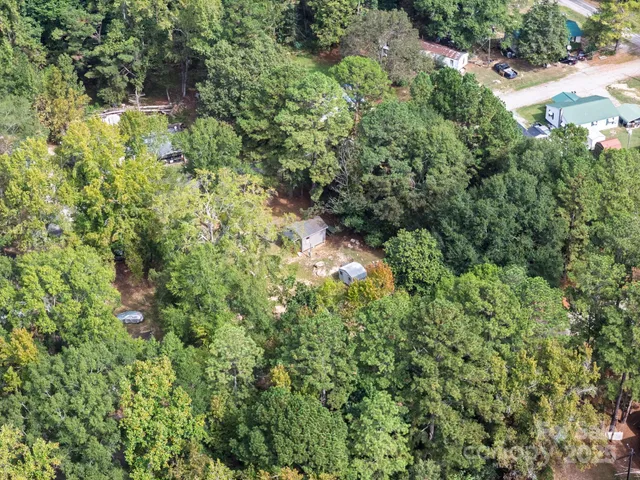 an aerial view of residential house with outdoor space and trees all around