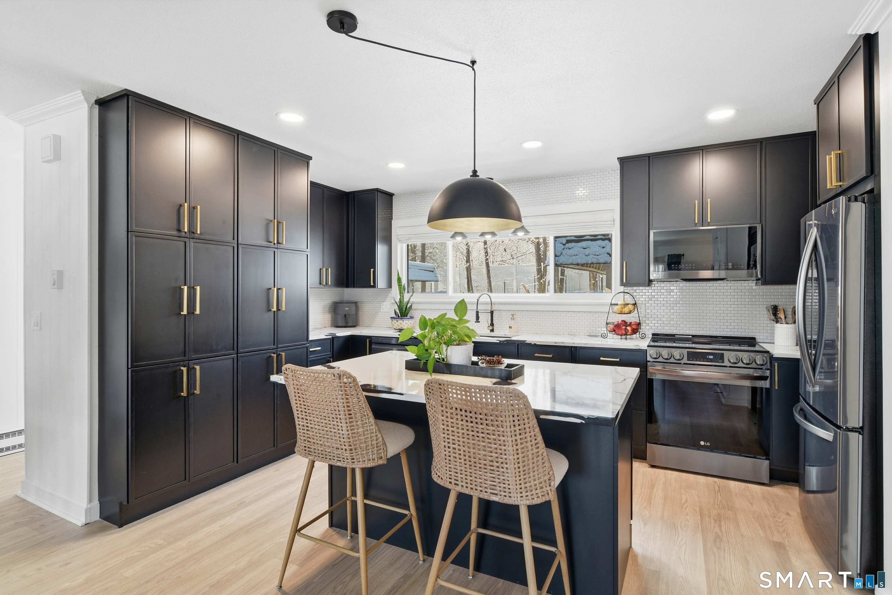 a kitchen with stainless steel appliances granite countertop a refrigerator a sink a stove a dining table and chairs