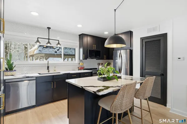 a kitchen with stainless steel appliances a dining table chairs and white cabinets