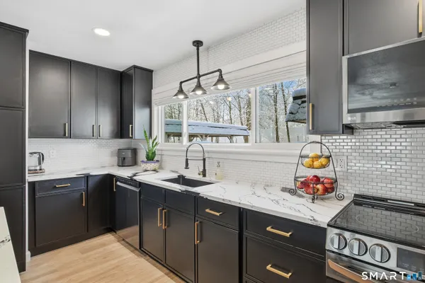 a kitchen with stainless steel appliances granite countertop a sink stove and cabinets