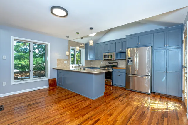 a kitchen with stainless steel appliances granite countertop a refrigerator stove a sink dishwasher and wooden cabinets with wooden floor