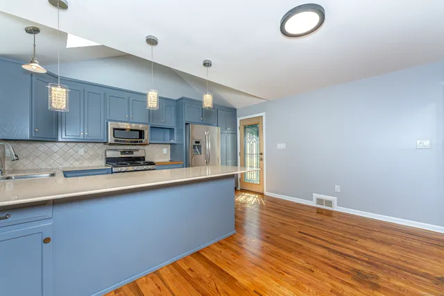 a large kitchen with stainless steel appliances granite countertop a sink and cabinets with wooden floor